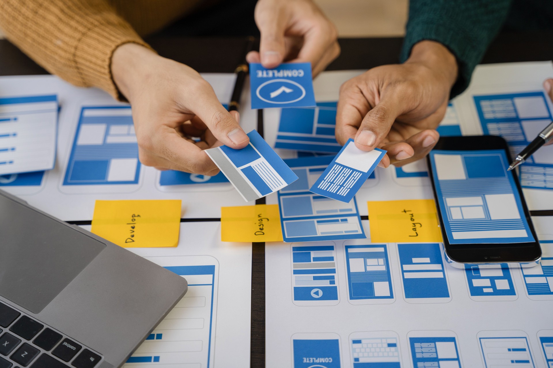Agencia creativa de desarrollo digital. Equipo de desarrolladores haciendo una lluvia de ideas sobre su proyecto con computadora portátil, teléfono inteligente y tableta digital.